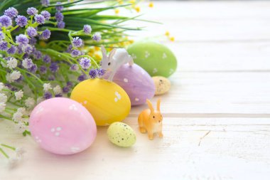 Çiçekli Paskalya yumurtaları ve tahta tahtada küçük tavşan oyuncakları, Paskalya bayramı konsepti..