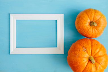 Mavi ahşap arka planda beyaz çerçeveli balkabakları Şükran Günü ve Cadılar Bayramı konsepti. Yukarıdan bak. Üst Manzara. Metin ve tasarım için boşluk kopyala
