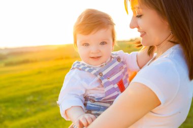 Anne ve çocuğu bahar tarlasında oynuyorlar yumuşak güneş ışığında