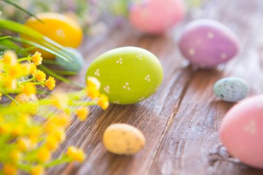 Kırsal ahşap arka planda çiçekli Paskalya yumurtaları ve dalları.
