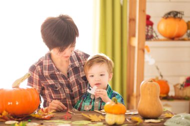 Mutlu aile anne ve çocuğu balkabağı oyuyor. Mutlu aile Cadılar Bayramı için hazırlanıyor.
