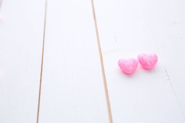 Beyaz boyalı ahşap arka planda asılı iki kalp.