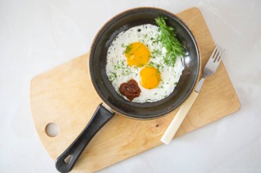 Tavada yumurta ve ahşap masa sapı.