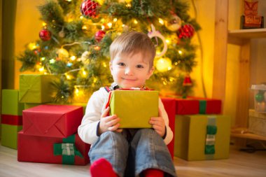 Noel arifesinde süslü odada Xmas hediyeli küçük mutlu çocuk. Güneşli bir sabah ya da gündüz. Noel ya da yeni yıl tatili.