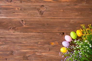 Kahverengi ahşap arka planda çiçekli renkli bir paskalya yumurtası. Yukarıdan görüntüle.