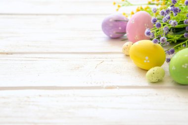 Kırsal ahşap arka planda çiçekler ve paskalya yumurtası süslemesi.