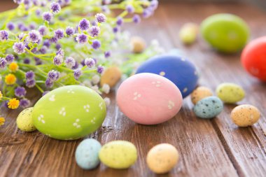 Eski kahverengi ahşap masada pastel renkte Paskalya yumurtaları