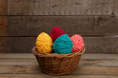 Ahşap masadaki yün iplikten yapılmış sepet paskalya yumurtalarıyla süslenmiş renkli. Mutlu Paskalyalar.