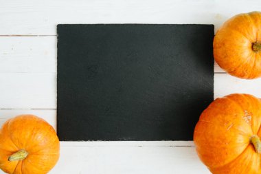 Balkabakları tahta arka planda ve siyah taş yüzeyde. Şükran Günü ve Cadılar Bayramı konsepti. Yukarıdan bak. Üst Manzara. Metin ve tasarım için boşluk kopyala