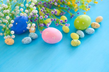 Güzel Paskalya yumurtaları ve çiçekler mavi ahşap arka planda, yakın plan