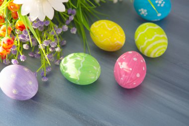 Renkli paskalya süsü ve gri ahşap bir masa üzerinde çiçekler. Üst görünüm