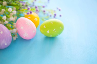 Mavi ahşap üzerine el boyanmış çok renkli paskalya yumurtaları..