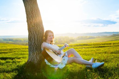 Sahada gitar çalan güzel bir genç kız. Mercek parlaması, seçici odak, tonlu resim.