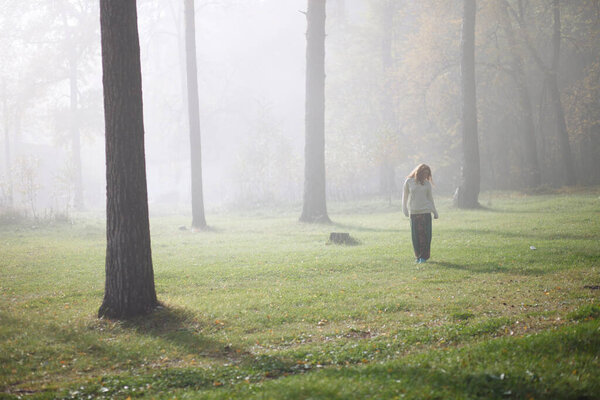 Woman walking in foggy forest during autumn