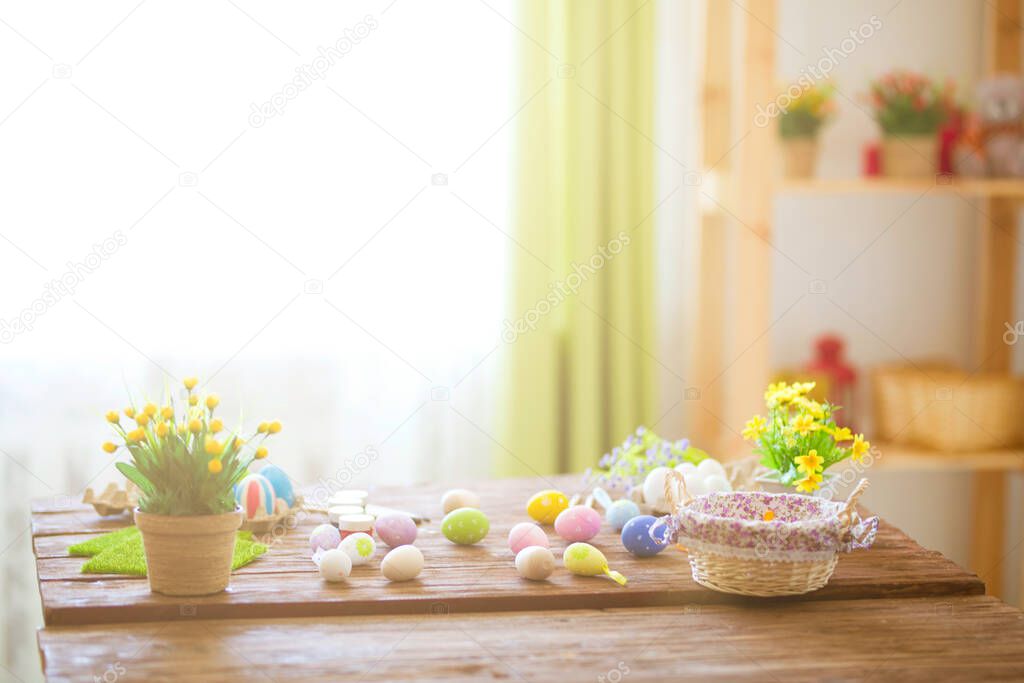 Colorful easter eggs and brushes on wooden table in home.