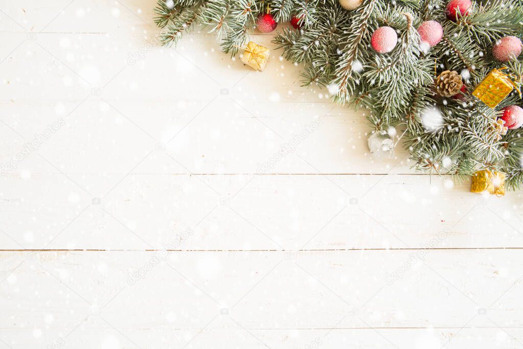 Fir branch with Christmas decorations on the white wooden table or plank background.