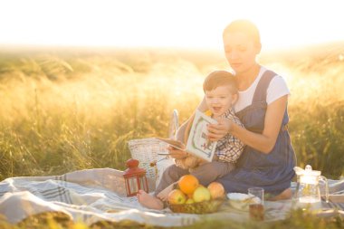 Küçük tatlı oğlan ve güzel hamile annesi piknikte.