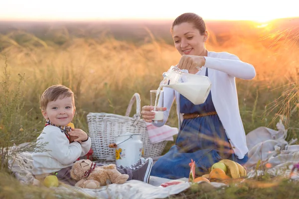 A kisfiú és a terhes anyja piknikeznek. — Stock Fotó