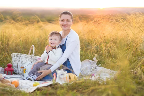A kisfiú és a terhes anyja piknikeznek. — Stock Fotó