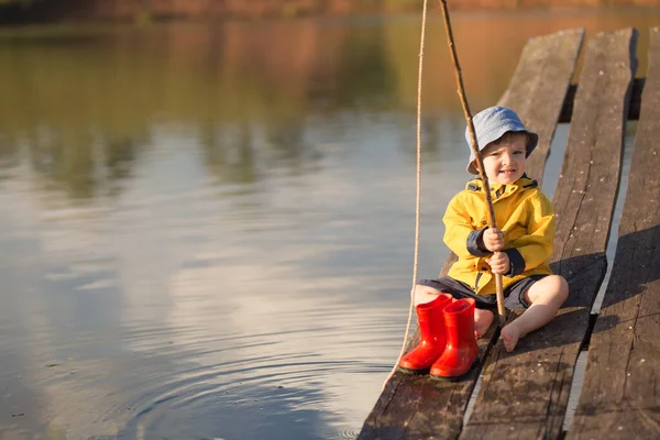 Kleiner Junge fängt einen Fisch vom Holzsteg — Stockfoto