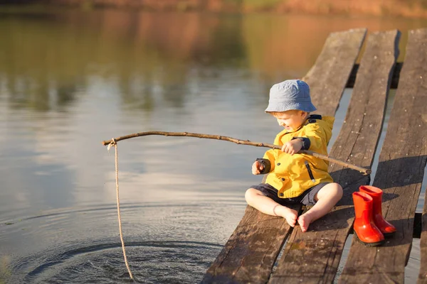 Pequeño niño la captura de un pez desde el muelle de madera — Foto de Stock