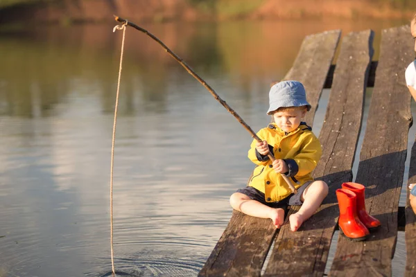 Pequeño niño la captura de un pez desde el muelle de madera —  Fotos de Stock