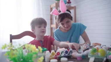 Mutlu Paskalyalar. Paskalya için yumurta boyayan bir anne ve oğul.