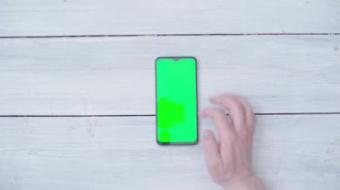 Masada krom anahtarı olan akıllı telefonlu bir erkek eli. Yukarıdan görüntüle