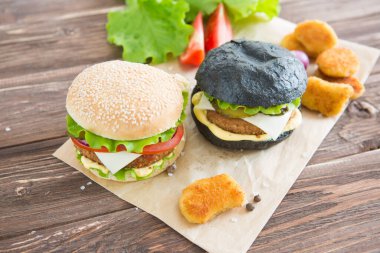 İki hamburger, sığır burger pirzolası, kızarmış soğan, ıspanak, ketçap sosu ve mavi peynirli geleneksel çörekler, koyu ahşap zemin üzerinde ahşap kesme tahtasında servis ediliyor..