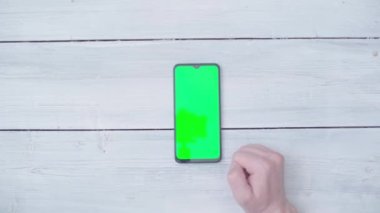 Masada krom anahtarı olan akıllı telefonlu bir erkek eli. Yukarıdan görüntüle