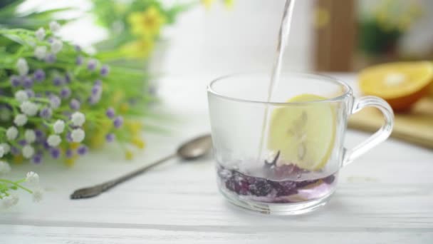 El té se vierte en una taza transparente de vidrio sobre una mesa de madera — Vídeos de Stock