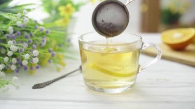 Çay, ahşap bir masada cam şeffaf bir fincana dökülür.
