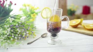 Çay, ahşap bir masada cam şeffaf bir fincana dökülür.