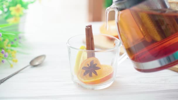 El té se vierte en una taza transparente de vidrio sobre una mesa de madera — Vídeos de Stock