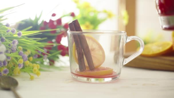 Tee wird in eine gläserne transparente Tasse auf einem Holztisch gegossen — Stockvideo