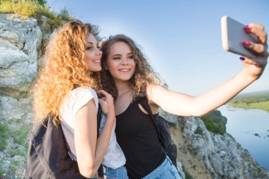 Dağlarda yürüyüş yapan iki kız selfie çekiyor.