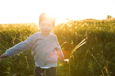 Sıcak bir yaz gününde, gün batımına karşı koşan bir çocuk.