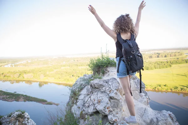 Eine Welt ohne Grenzen. Das Mädchen auf dem Gipfel des Berges mit einem Rucksack. Das Konzept von Reisen und Erfolg Stockbild