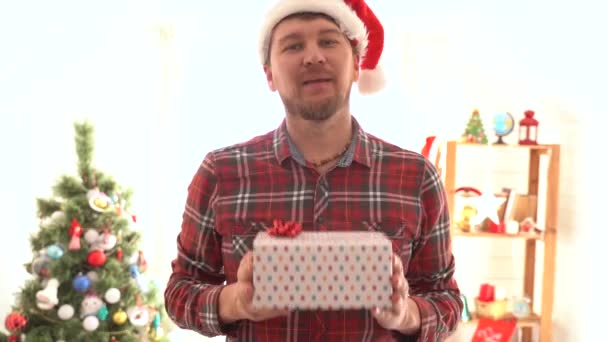 En man i rutig skjorta ger en julklapp — Stockvideo