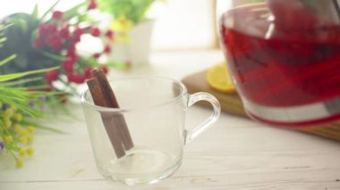 Çay, ahşap bir masada cam şeffaf bir fincana dökülür.