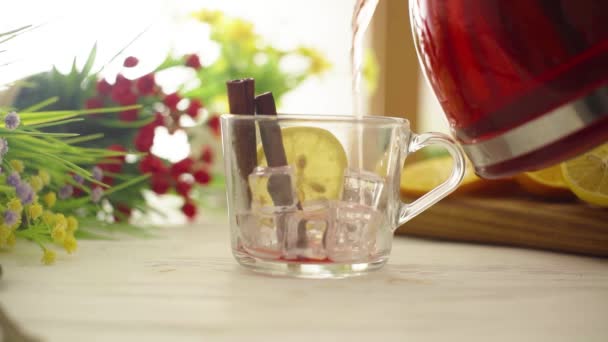 Tee wird in eine gläserne transparente Tasse auf einem Holztisch gegossen — Stockvideo