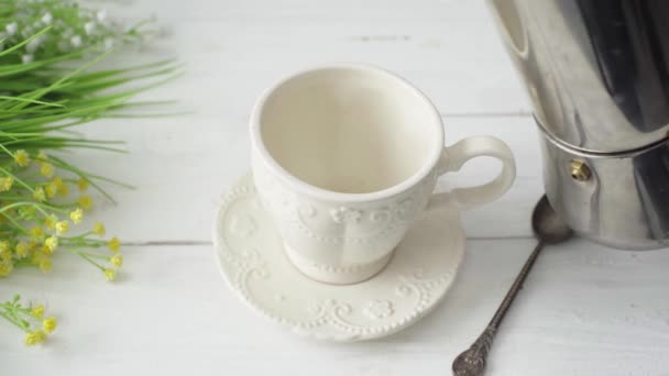 Νόστιμο αναζωογονητικό καφέ χύνεται σε ένα όμορφο φλιτζάνι πορσελάνη σε ένα λευκό τραπέζι — Αρχείο Βίντεο