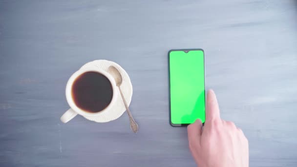 Ένα χέρι mans χρησιμοποιεί ένα smartphone με ένα κλειδί chroma και αναμιγνύει τον καφέ με ένα κουτάλι — Αρχείο Βίντεο