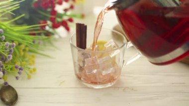 Çay, ahşap bir masada cam şeffaf bir fincana dökülür.