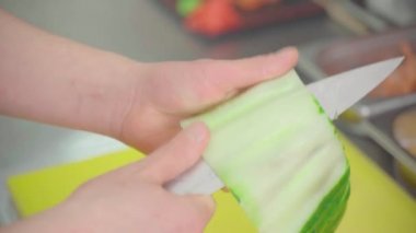 Bir salatalığı ince şeritlere ayırır.