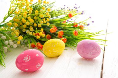 Paskalya yumurtaları ve çiçekler beyaz ahşap kalaslarda