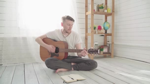 Um homem com uma guitarra a compor uma canção — Vídeo de Stock