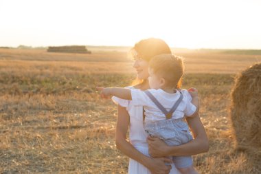 Anne gün batımında parkta yürürken çocuğuna sarılıyor.