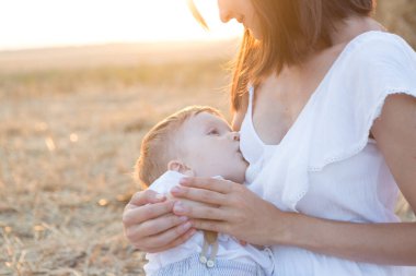 Güzel mutlu anne bebeğini dışarıda emziriyor..