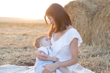 Güzel mutlu anne bebeğini dışarıda emziriyor..